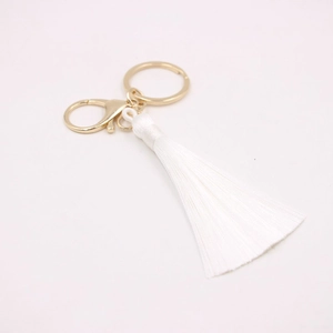 Détail macro du porte-clés à pompon en soie blanche avec fermoir mousqueton doré