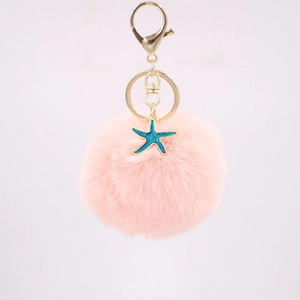 Close-up of fluffy pink pom pom keychain with turquoise starfish and golden lobster clasp