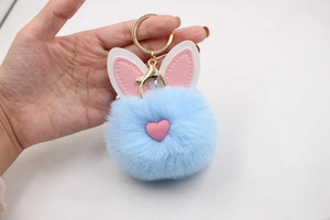 Dettaglio portachiavi pompon azzurro in ecopelliccia con orecchie da coniglio e gancio dorato