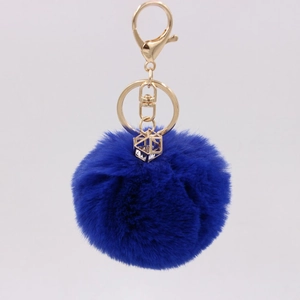 Macro shot of a royal blue faux fur keychain with a gold crystal geometric charm and clip