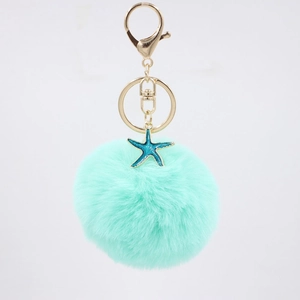Mint green faux fur pompom keychain with a blue starfish pendant and gold metal hardware