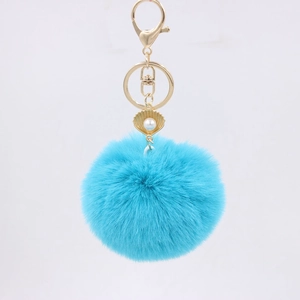 Close-up of fluffy blue faux fur keychain with gold shell pearl pendant and lobster clasp