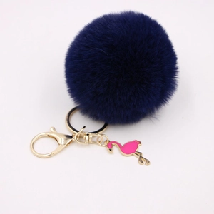 Detailed macro view of navy blue fluffy pompom keychain with pink flamingo charm and gold clip
