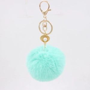 Close-up of mint green faux fur keychain with golden shell pendant and pearl detail