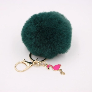 Detailed close-up of dark green faux fur pompom keychain with golden flamingo charm
