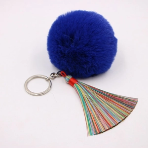 Makro-Detail von königsblauem Plüsch-Bommel mit bunten Regenbogen-Seidenquasten und Silberring