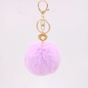 Detail of light purple faux fur pompom keychain with gold lobster clasp and pearl shell charm