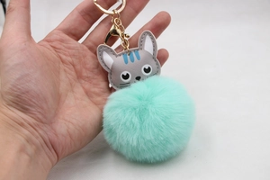 Détail du porte-clés pompon vert menthe avec charme chat en cuir gris et anneau doré
