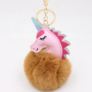 Close-up of pink unicorn keychain with a large brown faux fur pompom and golden clip