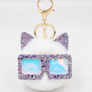 Détail d'un porte-clés chat en peluche blanc avec oreilles pailletées et lunettes hologramme