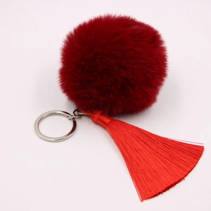 Close-up of soft red faux fur pompom and silky tassel keychain with silver ring