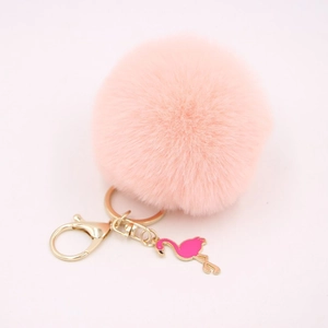Close-up of pink fluffy pompom keychain with golden metal ring and flamingo charm