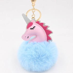 Detail of blue plush pom-pom unicorn keychain with gold clasp and pink leather head