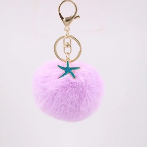 Purple plush pom pom keychain featuring a golden starfish charm and lobster clasp attachment