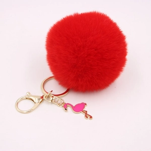 Close-up of bright red faux fur pompom keychain with golden clasp and flamingo charm