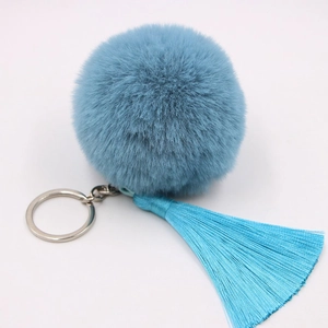 Detail of light blue fluffy pom pom keychain with matching silk tassels and silver ring