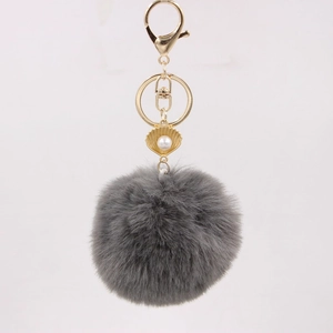 Close-up of gray faux fur pompom keychain with golden shell pendant and pearl detail