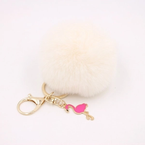 Detail of a fluffy cream faux fur pompom keychain with a pink flamingo enamel charm