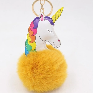 Détail d'un porte-clés licorne en peluche jaune avec crinière arc-en-ciel et pompon doux