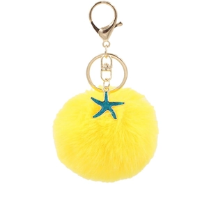Yellow faux fur pom pom keychain with a turquoise starfish pendant and golden metal rings