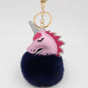 Close-up of pink leather unicorn keychain with dark blue pompom and golden clasp