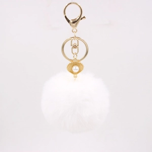 Detailed close-up of fluffy white pom-pom keychain with gold shell and pearl charm