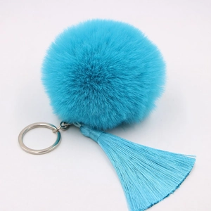 Detail shot of fluffy sky blue faux fur pompom with long tassel and silver metal keyring