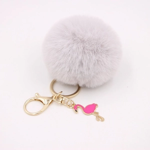 Detail of grey faux fur pom pom keychain with gold ring and pink enamel flamingo charm