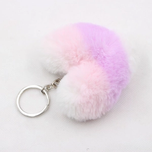 Macro shot of colorful heart-shaped plush keychain with soft white pink and purple gradient fur
