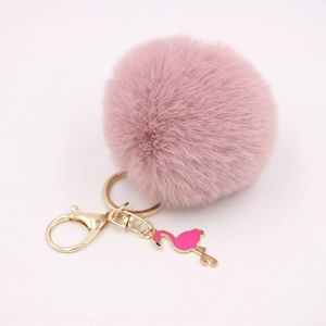 Detailed close-up of pink fluffy pompom keychain with golden flamingo charm and clasp