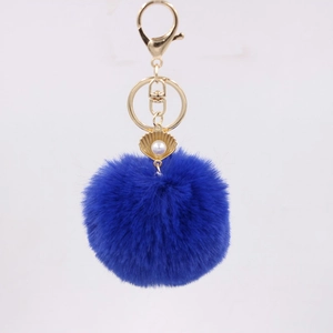 Detailed view of plush navy blue fur ball keychain with golden shell and pearl charm