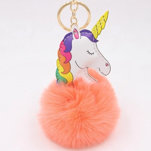 Détail d'un pompon en fausse fourrure corail avec pendentif tête de licorne blanche