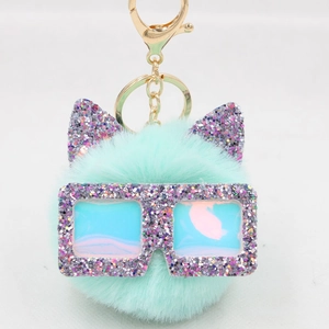 Détail du porte-clés en peluche vert menthe avec oreilles de chat et lunettes à paillettes