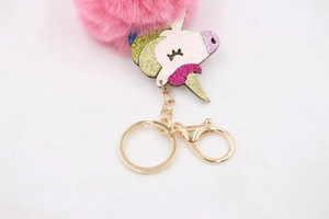 Detail of pink fluffy pompom keychain with sequin unicorn head and golden clasp