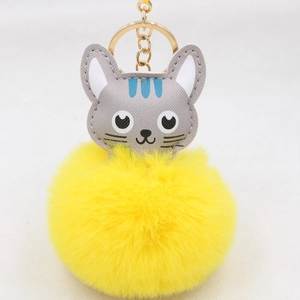 Vue détaillée du porte-clés chat en pompon jaune avec cuir gris et anneau en métal doré