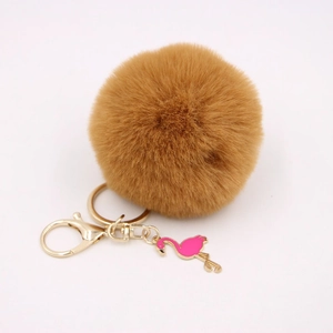 Close-up of fluffy brown pompom keychain with golden lobster clasp and pink flamingo charm
