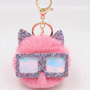 Détail du porte-clés en fourrure rose avec oreilles pailletées et lunettes hologrammes