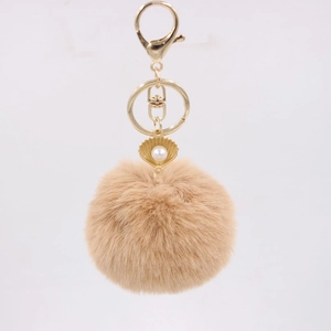 Detail of khaki faux fur keychain with golden shell charm and white pearl accent