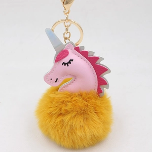 Close-up of pink leather unicorn head with yellow fluffy pom pom and golden keychain clasp