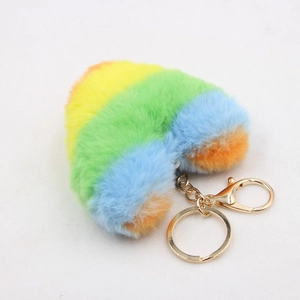 Detailed macro view of heart-shaped faux fur keychain with rainbow stripes and golden clasp