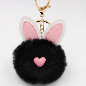 Dettaglio del portachiavi a forma di coniglio in peluche nera con cuore rosa e gancio dorato