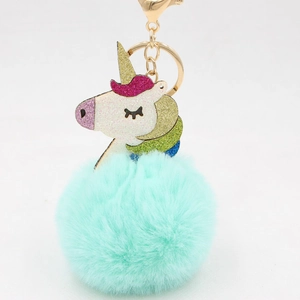 Detail of mint green pompom keychain with glittery unicorn charm and golden metal hook