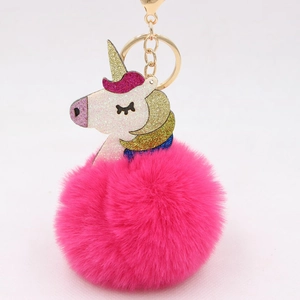 Detail of colorful unicorn keychain with pink faux fur pompom and golden glitter horn