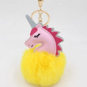Close-up of pink unicorn head with yellow faux fur pompom and golden keyring clip