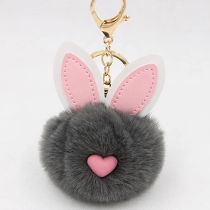 Dettaglio portachiavi pompon in finta pelliccia grigio scuro con cuore rosa e orecchie