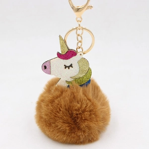 Detail of colorful glitter unicorn charm with brown faux fur pom pom and gold lobster clasp