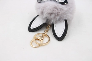 Detail of grey fluffy bunny keychain with black leather ears and gold metal clasp