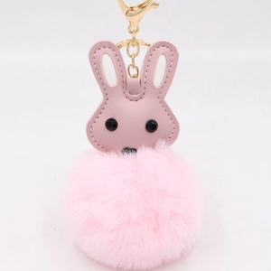 Gros plan du porte-clés lapin en peluche rose avec pompon doux et fermoir en métal doré
