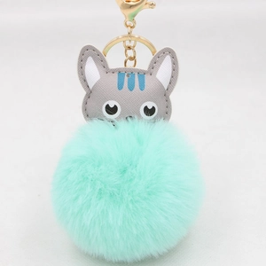 Détail d'une tête de chat grise en peluche avec pompon vert menthe et fermoir mousqueton doré