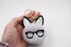 Detail of grey plush rabbit keychain with black sunglasses and gold metal hardware